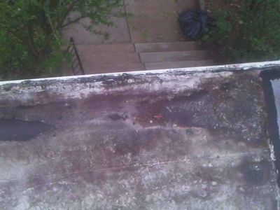 Deteriorated flat roof membrane with standing water and dark staining on a Germantown Philadelphia row home — found during a May 2026 home inspection