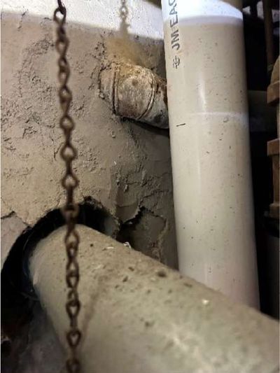 Cracked waste stack and aging drain piping in the garage of a Logan / Fern Rock North Philadelphia rowhome, documented during a June 2026 home inspection
