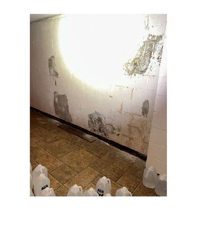 Concrete block foundation wall with multiple areas of dark discoloration and mineral deposits