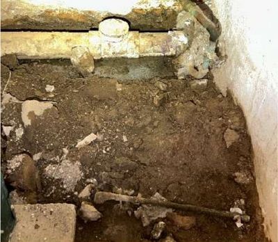 Main sanitary cleanout in the basement of a Germantown Philadelphia row home with soiled, disturbed floor around the fitting, indicating a drain leak found during a May 2026 home inspection