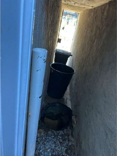 Heater discharge vent terminating in the narrow back-entry chase of a Lawncrest Northeast Philadelphia row home, flagged as a safety hazard during a home inspection