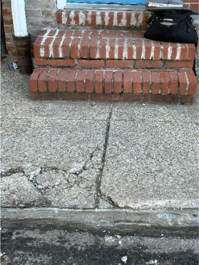 Cracked and settled front sidewalk over the main waste drain at a Lawncrest Philadelphia row home, documented during a home inspection