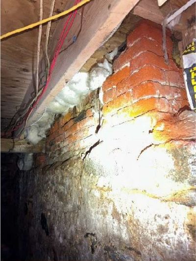 Basement support post bearing on a deteriorated brick wall pocket with crumbling mortar in a Fishtown mixed-use rowhome, found during a May 2026 home inspection