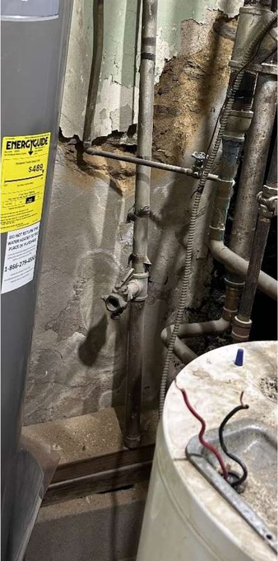 Rusted and unsupported water supply lines running through an opening in the ceiling of a converted Fern Rock Philadelphia rowhome, found during a home inspection