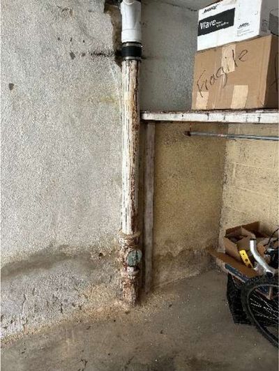 Corroded original cast-iron waste stack with rust scale at the base in the basement of 7015 Large St Northeast Philadelphia, documented during a May 2026 home inspection