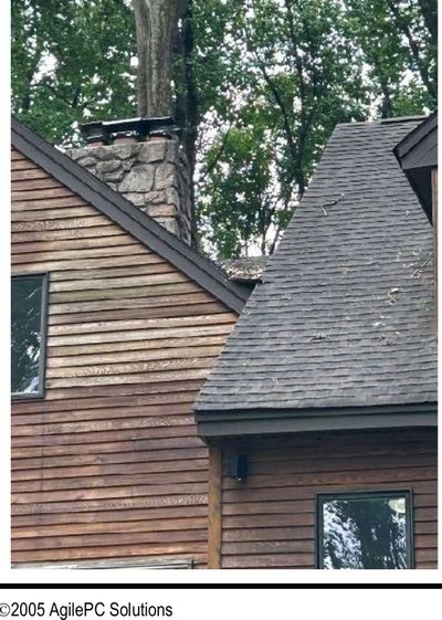 Wood-sided home roof edge with no gutters or downspouts above weathered siding in Schwenksville PA, documented during a June 2026 home inspection