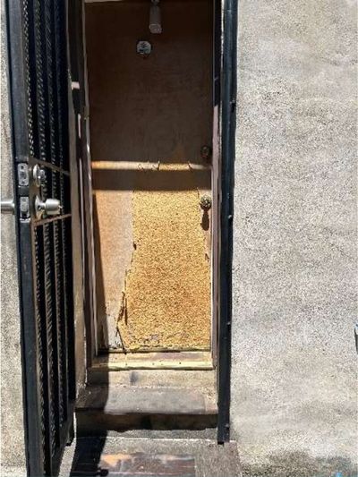 Corroded steel basement walkout doors over rotted wood stairs with no handrail at a Northern Liberties Philadelphia storefront, found during a May 2026 home inspection
