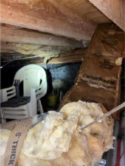 Fallen fiberglass insulation and stored items on the ground in the crawl space of a Phoenixville PA home, documented during a July 2026 home inspection