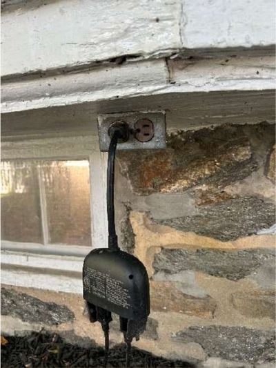 Uncovered exterior receptacle with reverse polarity and no GFCI on the stone foundation of a Roxborough Philadelphia home, found during a June 2026 home inspection