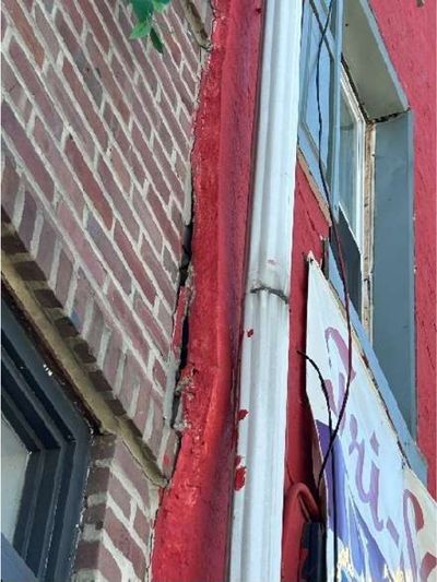 Shifting and cracked front stucco facade separating from brick at a Northern Liberties Philadelphia storefront, documented during a May 2026 home inspection