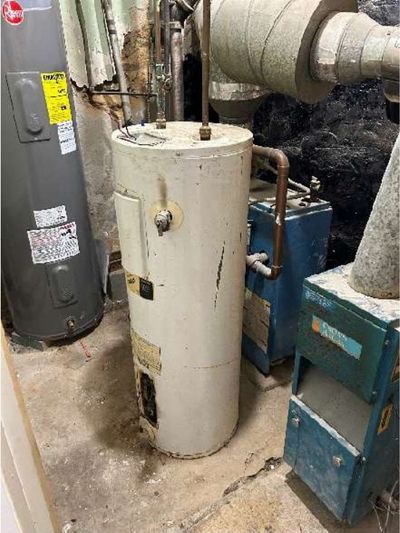 Corroded hot water heater next to an aging boiler in the basement of a converted Fern Rock Philadelphia rowhome, found during a home inspection