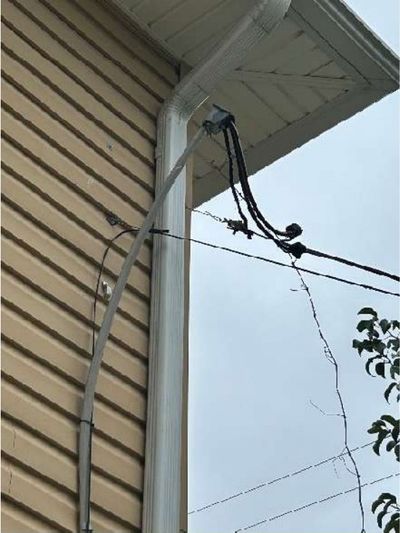 Unsecured electrical service entrance cable pulling away from the eave of a pre-war Willow Grove PA home, found during a July 2026 home inspection